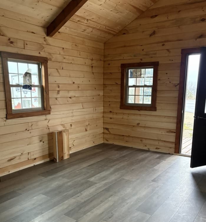 Small log cabin interior with natural light pine wood paneling and modern gray-brown flooring